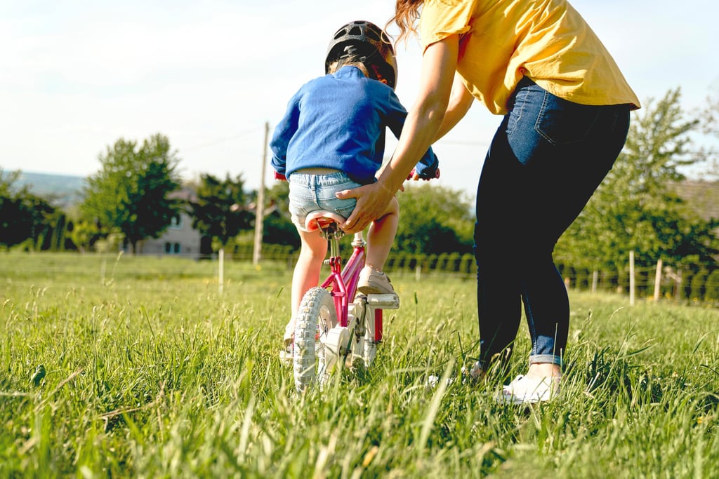 a woman in a yellow shirt and jeans and a helmet on a bicycle