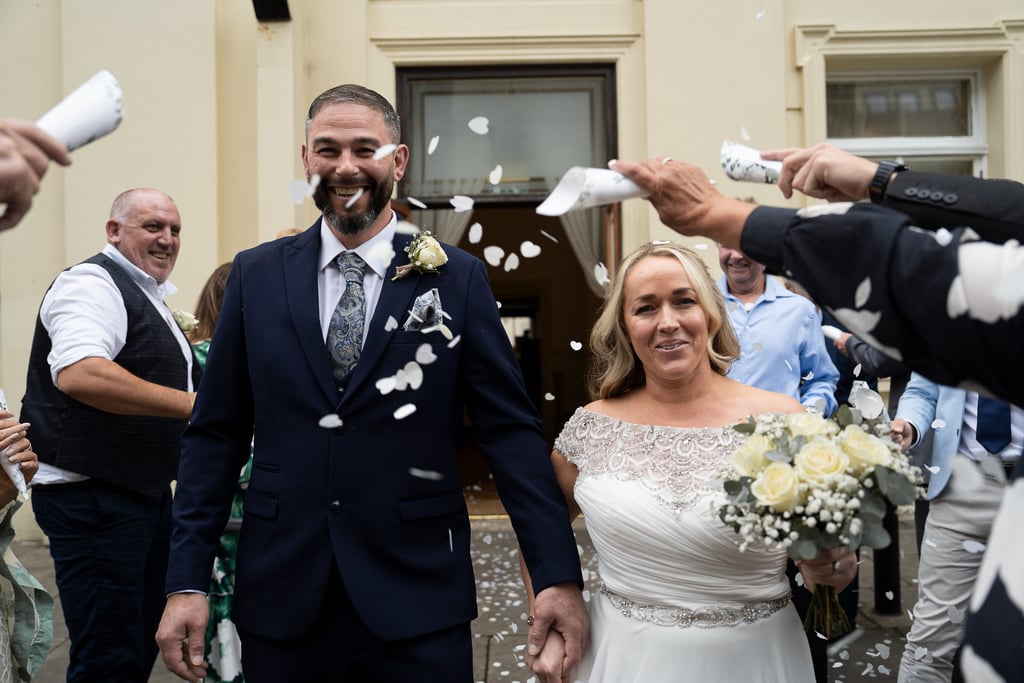 Newly married couple smiling during confetti 