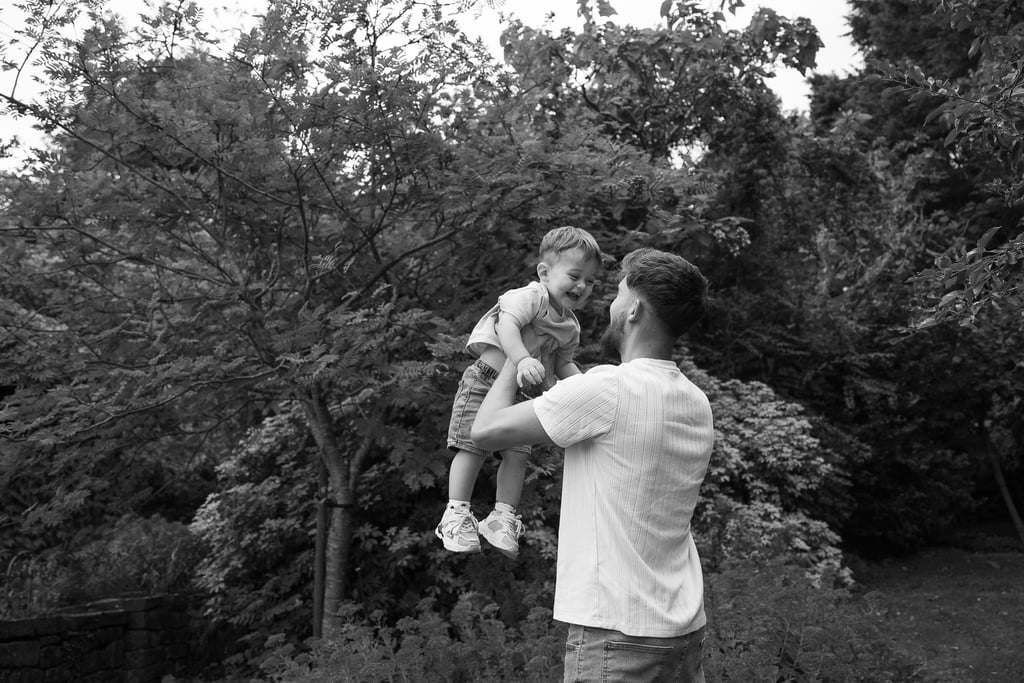 Black and white image father holding up baby boy 