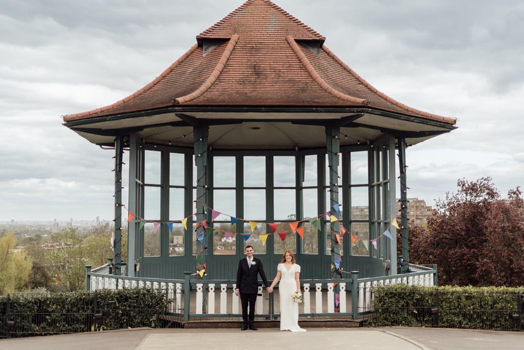 Bride and groom holding hands standing infront of band stand