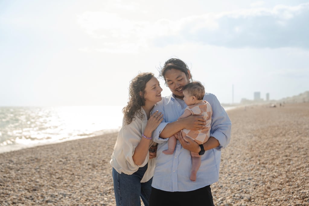 Family holding their baby on the beach during sunset