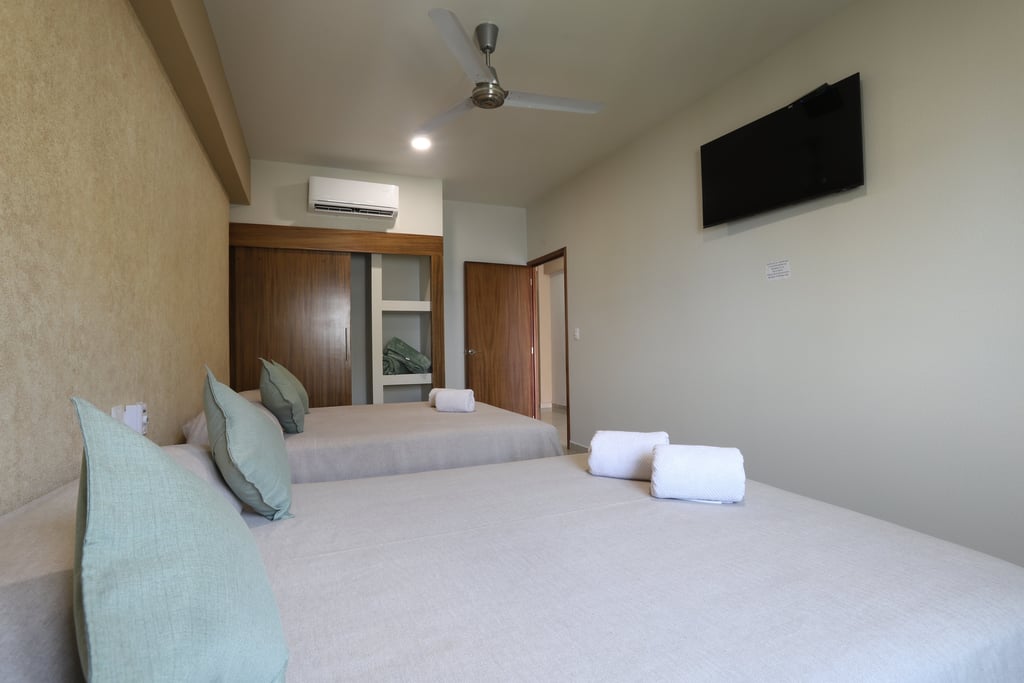 Habitacion con dos camas matrimoniales y un televisor en bungalows a pie de playa en Los Ayala