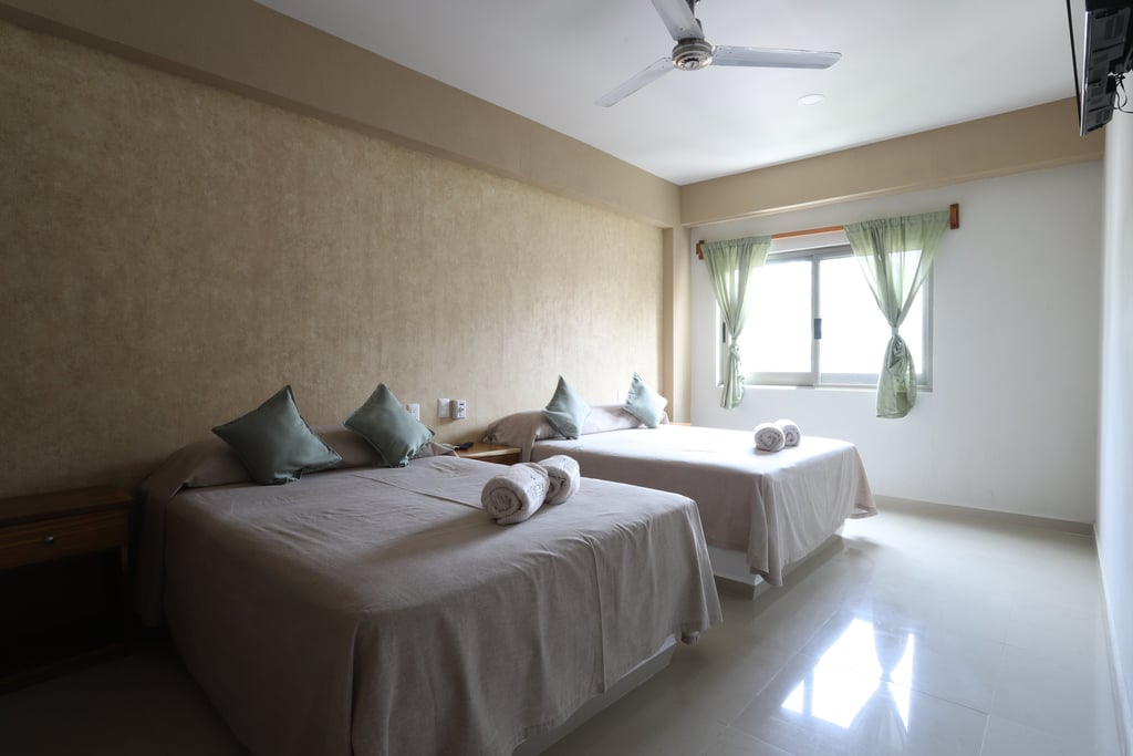 Habitacón con dos camas matrimoniales y una ventana de fondo