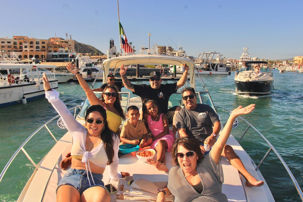 A happy family enjoys a sunny private boat tour in Cabo San Lucas harbor.