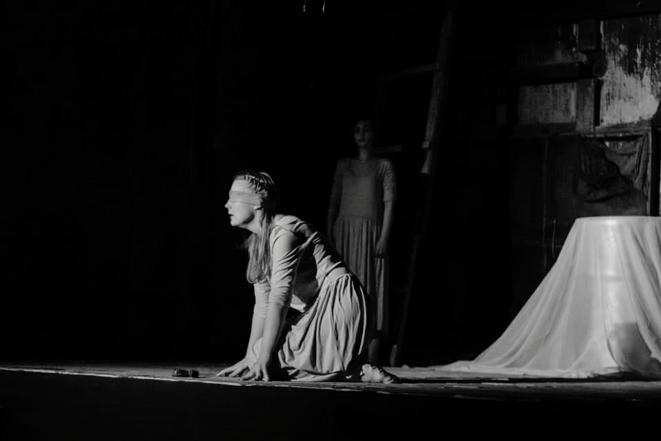 a woman in a long dress is kneeling on a stage