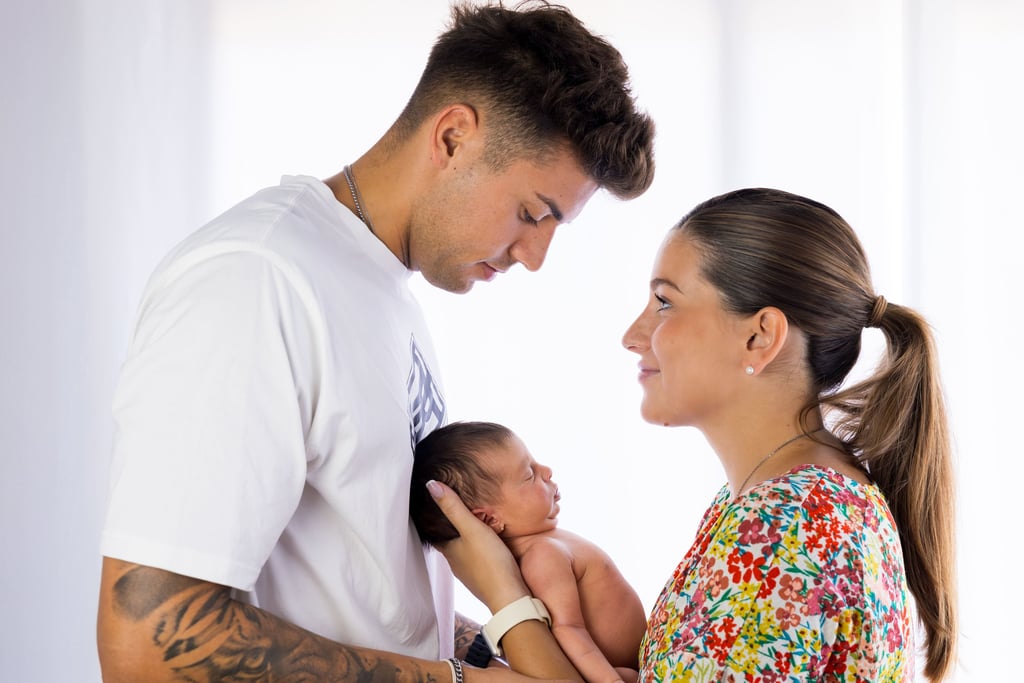 Sessió de fotos newborn a Girona amb una bebè dormint als braços dels pares en estudi fotogràfic