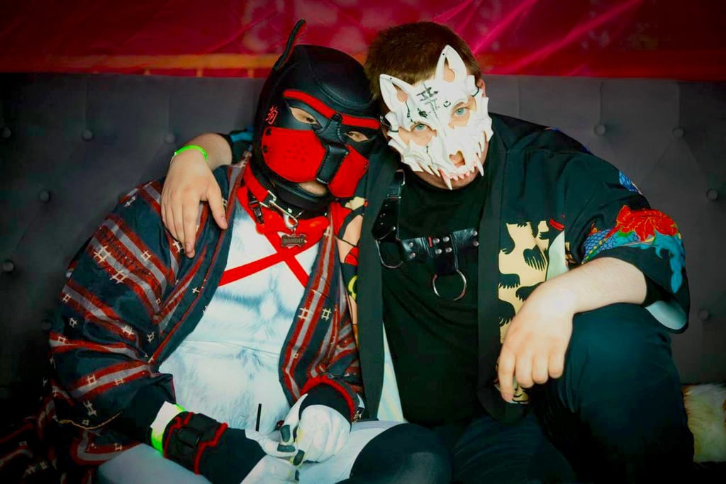 2 men in pup masks posing together.