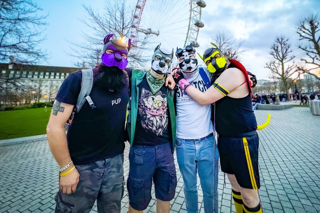Four friends posing in their pup masks at an amusement park.