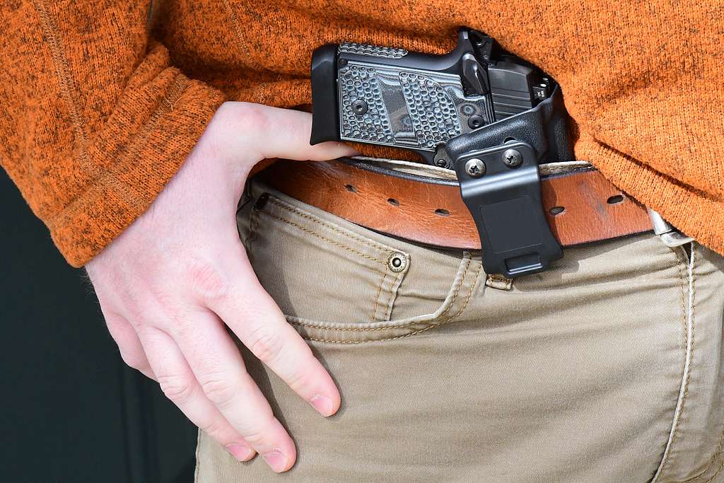 gun being concealed inside the waist band of a pair of pants