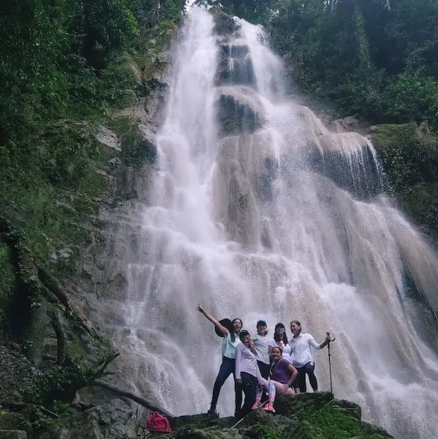 a group of people standing around a waterfall
