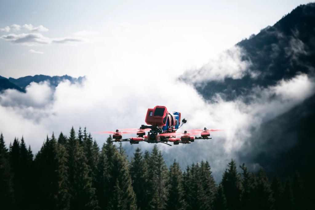 fpv drone strapped with a gopro and red propellers flying over a mountain range