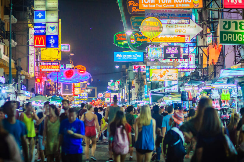 Nachts ein überfüllter Neon-Straßenmarkt in Bangkok, Thailand, mit leuchtenden Schildern