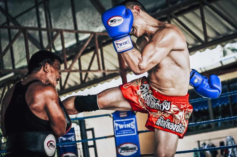 Professioneller Muay-Thai-Kämpfer setzt in einem Boxring einen kraftvollen Roundhouse-Kick gegen