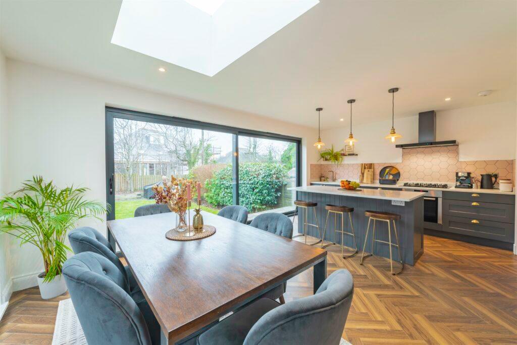 Modern open plan kitchen and dining area featuring a wood table, blue velvet chairs, and parquet flooring.