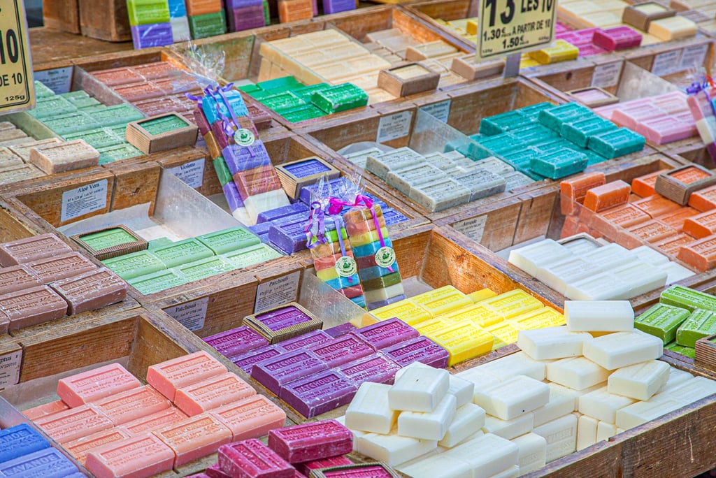 Display of colorful artisan soaps in wooden crates at an outdoor French market.