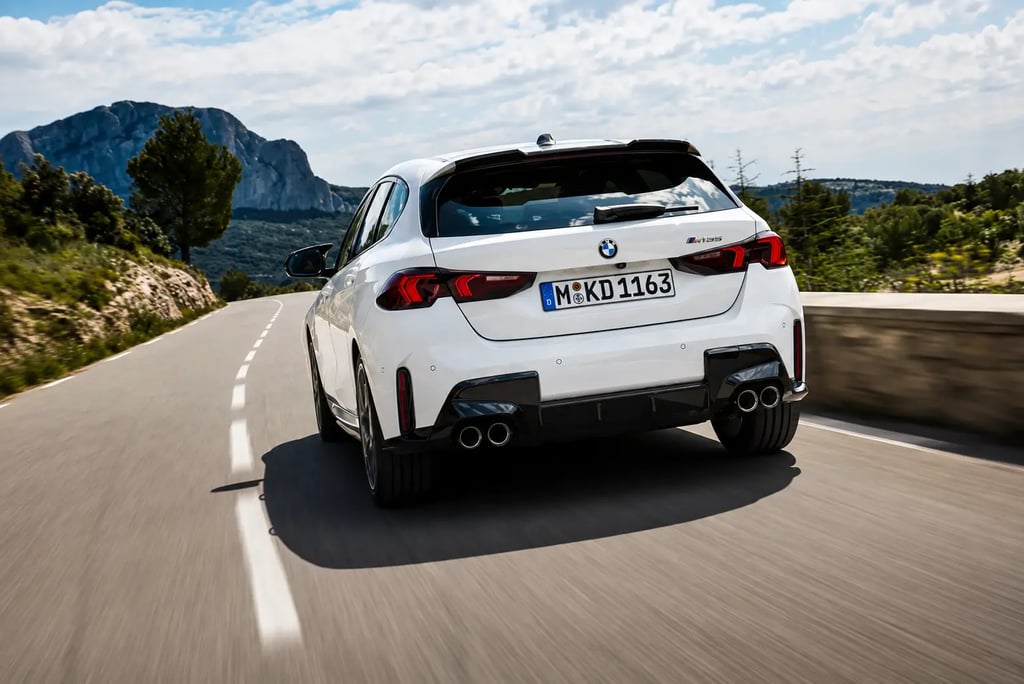 BMW hatch branco visto de traseira em estrada montanhosa com visual esportivo