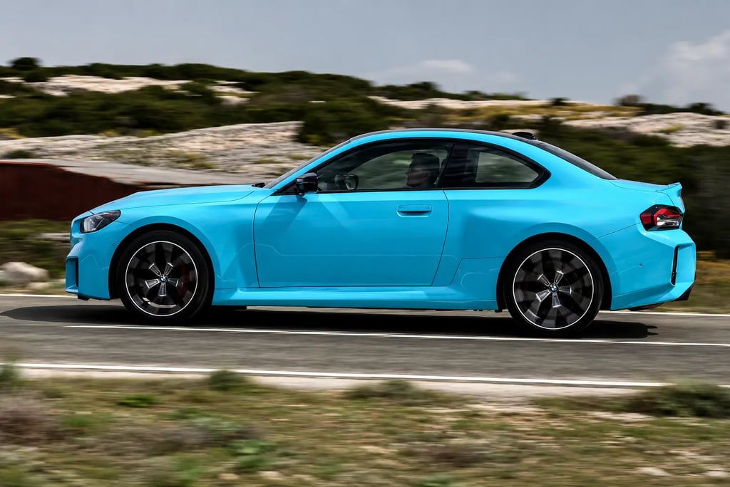 BMW M2 xDrive azul visto de perfil acelerando em estrada com visual esportivo