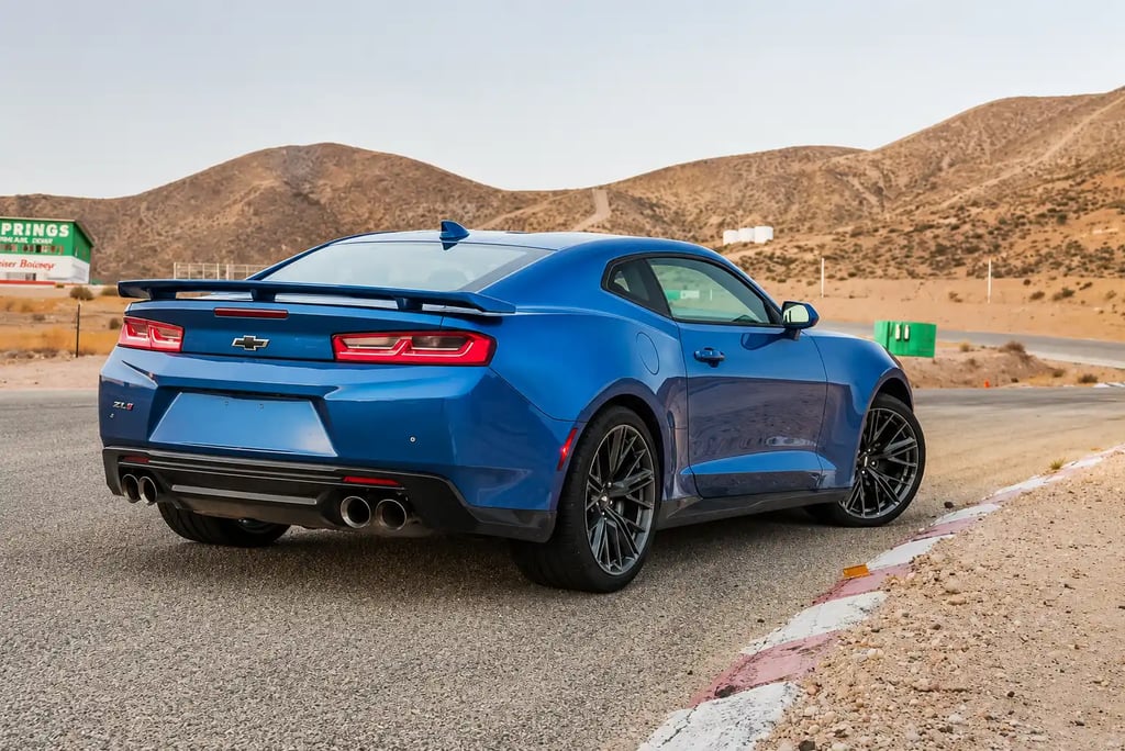 Chevrolet Camaro ZL1 azul visto por trás em pista cercada por montanhas desérticas
