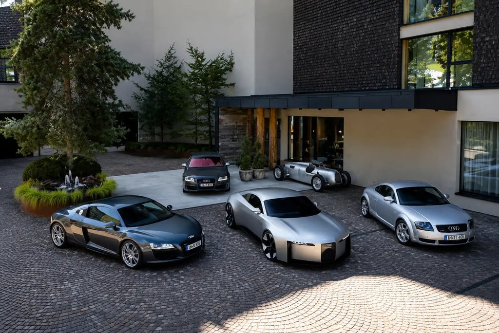 Linha de carros Audi mostra evolução do TT até novo conceito elétrico em pátio moderno.