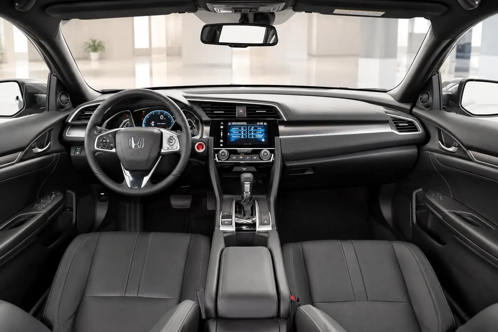 Interior do Honda Civic com painel e bancos em couro em showroom neutro e iluminação natural.
