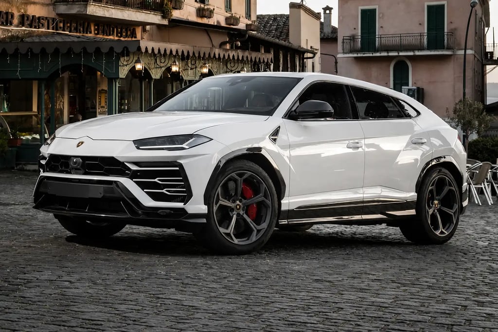 Lamborghini Urus branca estacionada em rua europeia de paralelepípedos.