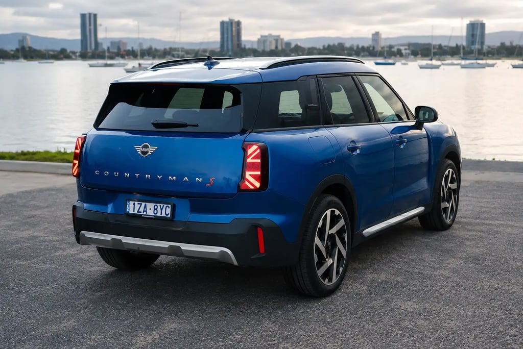 MINI Countryman azul visto de trás estacionado à beira-mar com skyline ao fundo