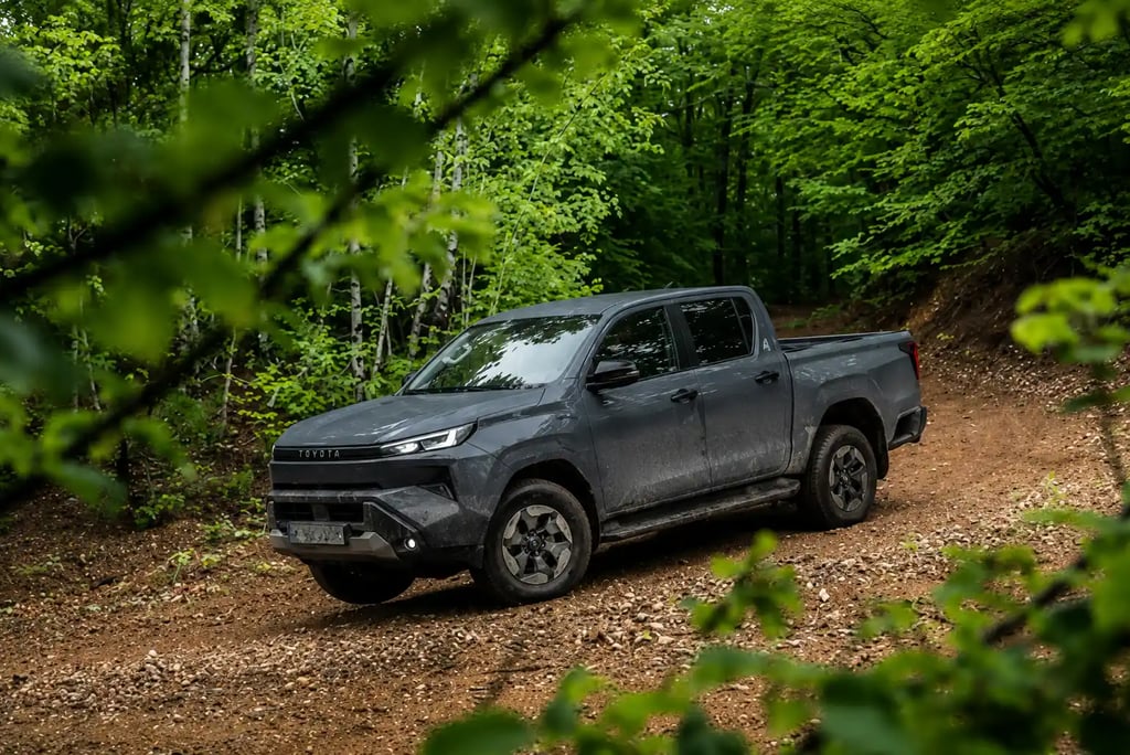 Nova Hilux elétrica em trilha de terra cercada por floresta durante teste off-road