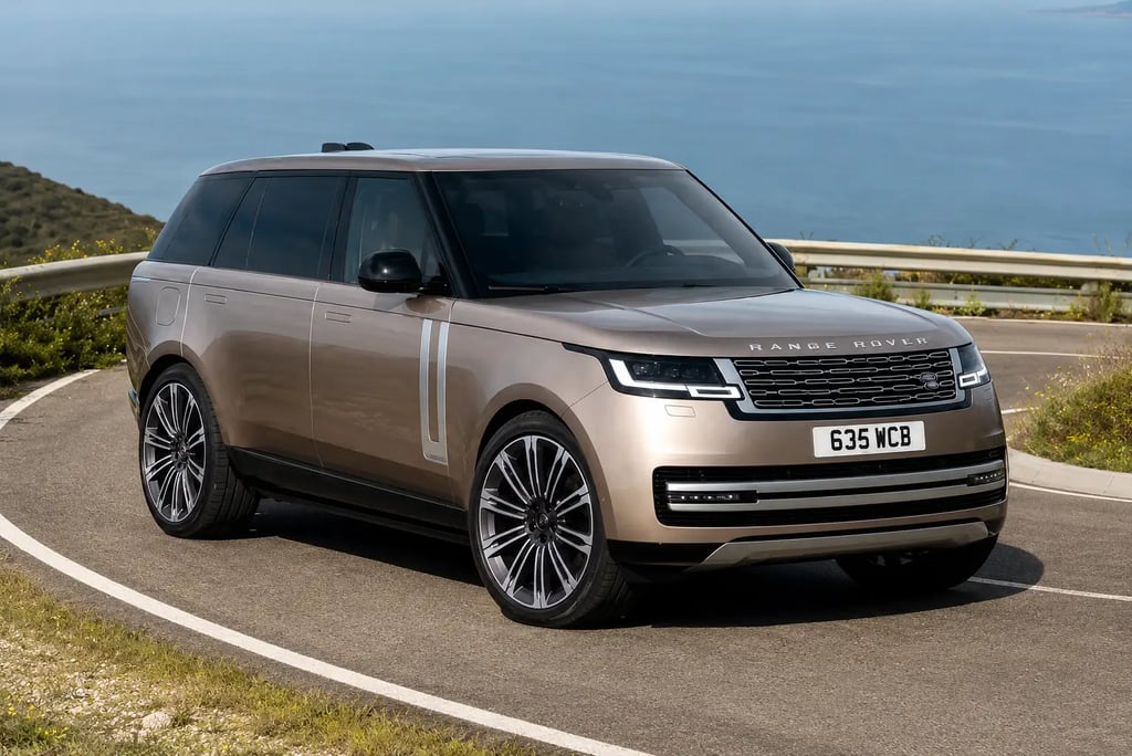 Range Rover de luxo em estrada costeira com vista para o mar.