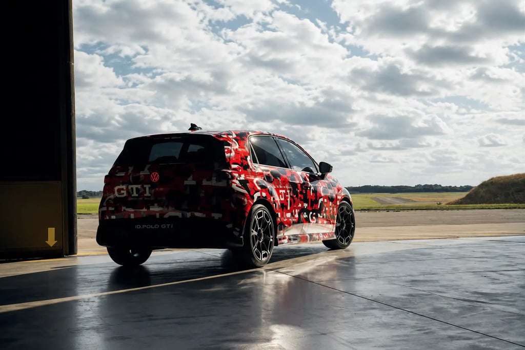VW ID.Polo GTI camuflado saindo de hangar em pista de testes ao pôr do sol