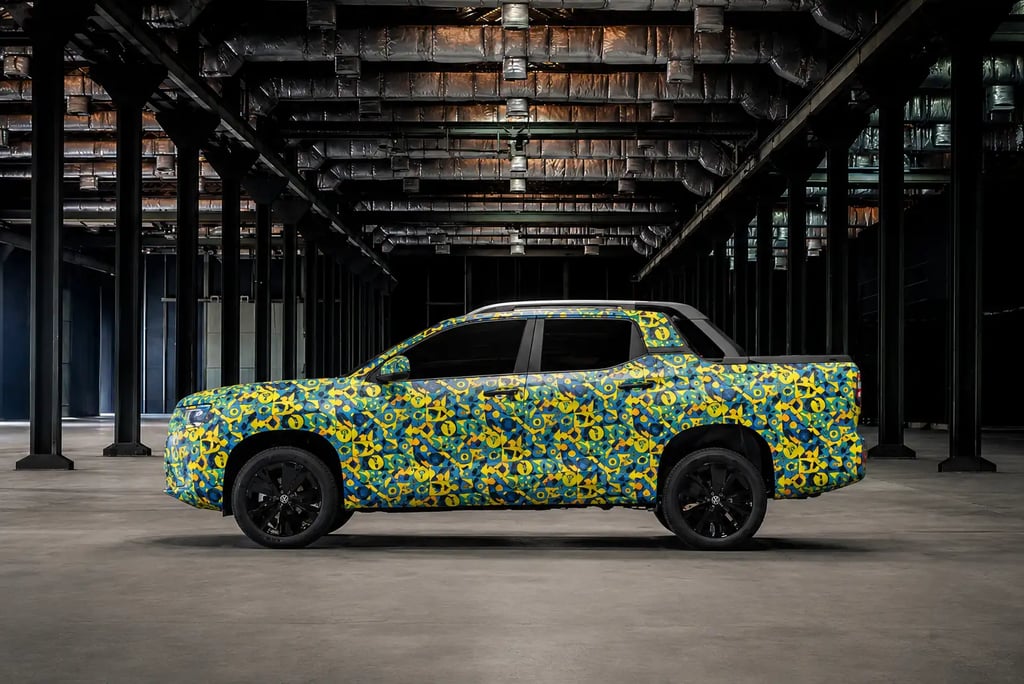 Vista lateral da nova picape VW Tukan camuflada em ambiente industrial moderno.