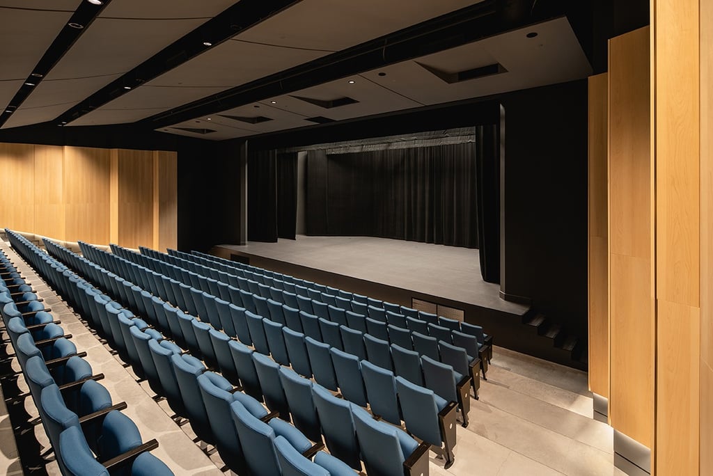 a theater stage with blue chairs and a stage