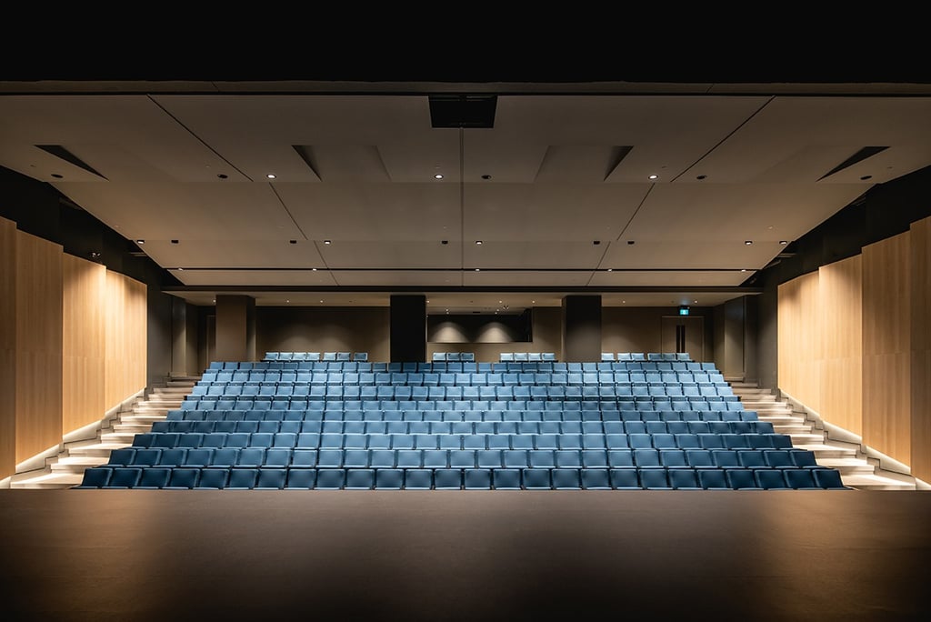 a large auditorium with blue chairs and a stage