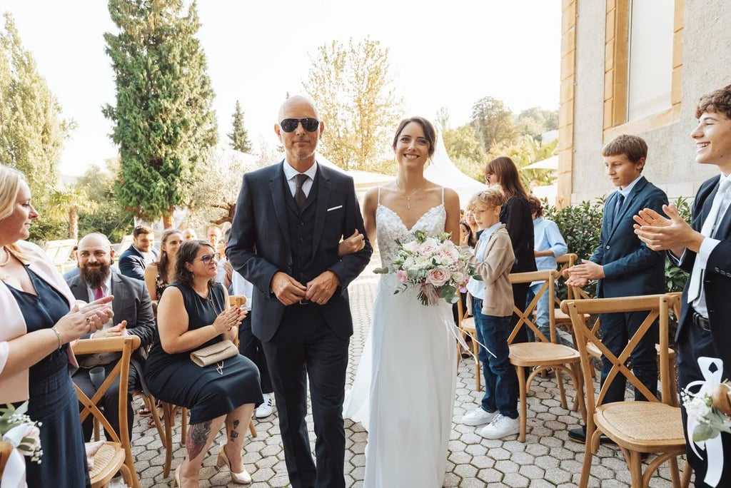 Entrée de la mariée au bras de son père, sous les regards des invités juste avant la découverte.