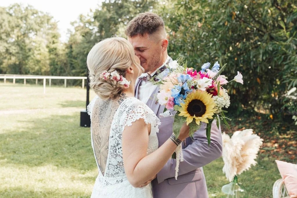 La mariée enlace le marié avec émotion lors de la découverte, bouquet coloré à la main.