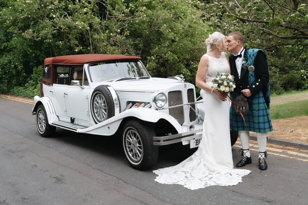 a bride and groom standing next to a car