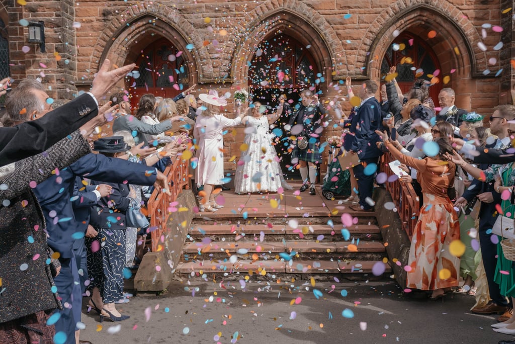 Wedding guests throw colorful confetti at a bride and groom exiting St Augustine’s church Coatbridge