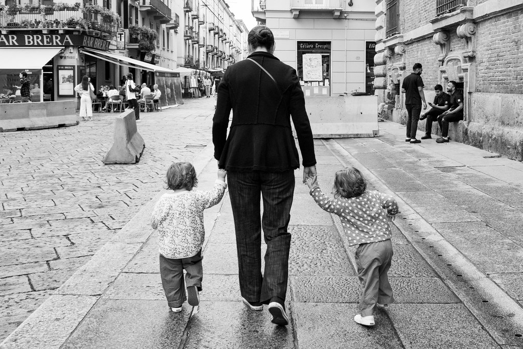 Mother takes her two children by the hand as the walk along the street in Milan, Italy