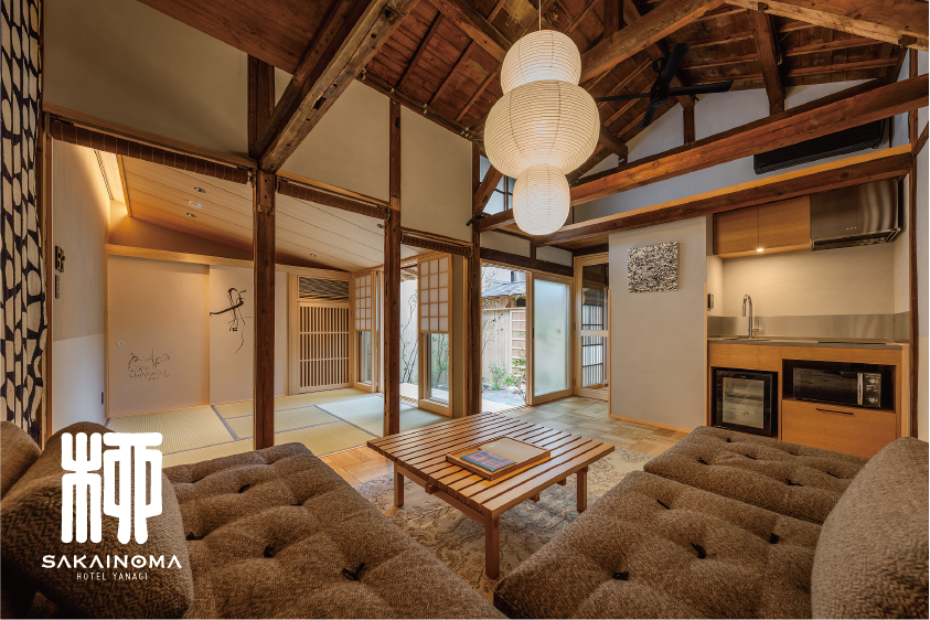 築200年の町家を改装した一棟貸切宿「SAKAINOMA HOTEL 柳」の客室内部。高い梁を見せた天井と畳の和室、中庭に面した縁側、檜風呂につながる落ち着いた空間が広がり、ソファやキッチンも備えられている様子|堺市のニュースならサカイタイムズ