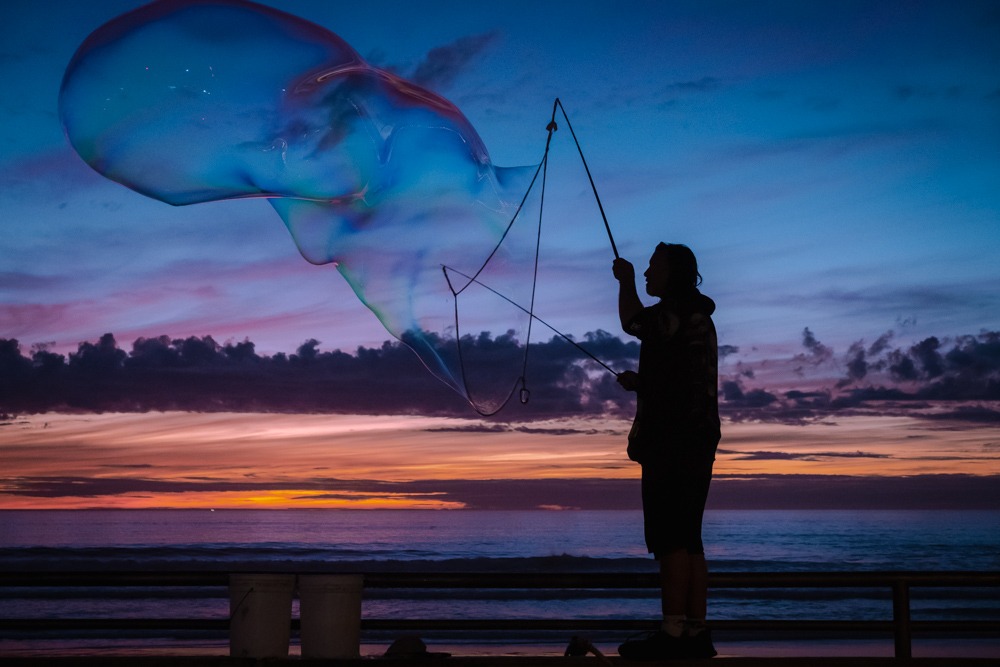 Silhouette of a man blowing giant bubbles against a sunset backdrop. Very peaceful feeling