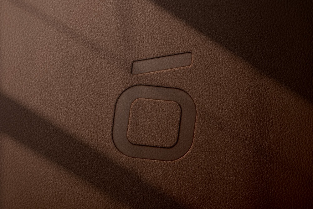 Embossed geometric logo design on premium brown textured leather background with dramatic shadows.