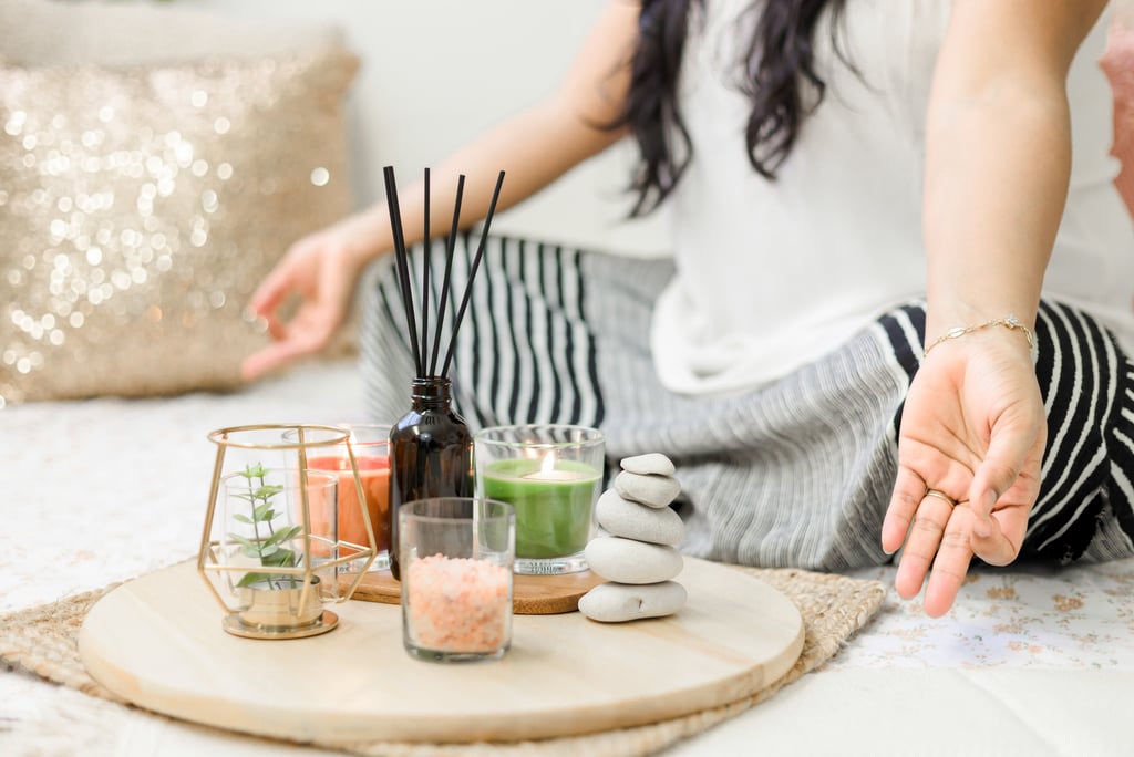 a woman sitting on a bed with candles and practice yoga part of herbal wellness