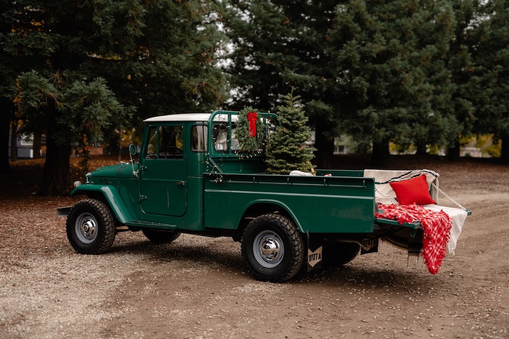 A photo of a green 1967 Toyota Land Cruiser pickup in a wooded setting.