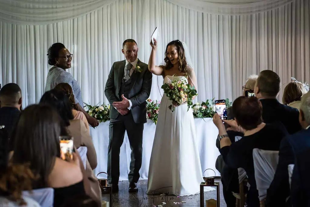 newly-weds holding their wedding certificate in the air