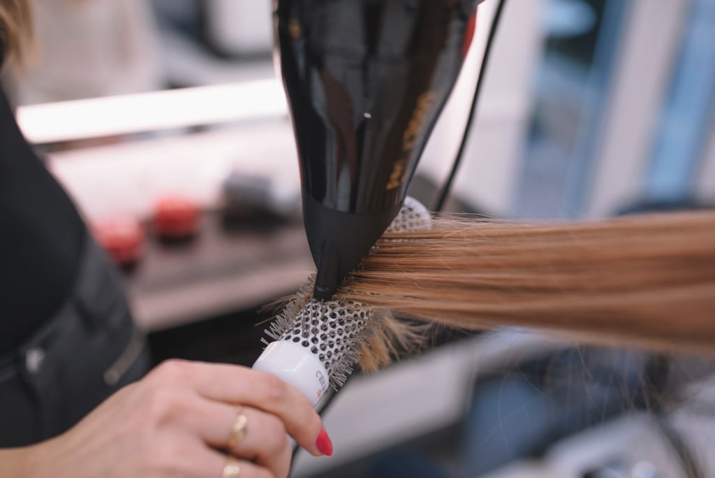 a woman is blow drying her hair in a salon