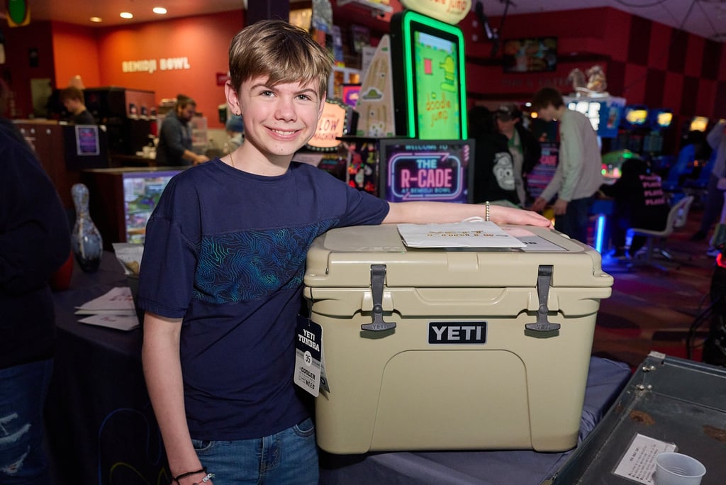 a boy standing next to a prize which is a cooler