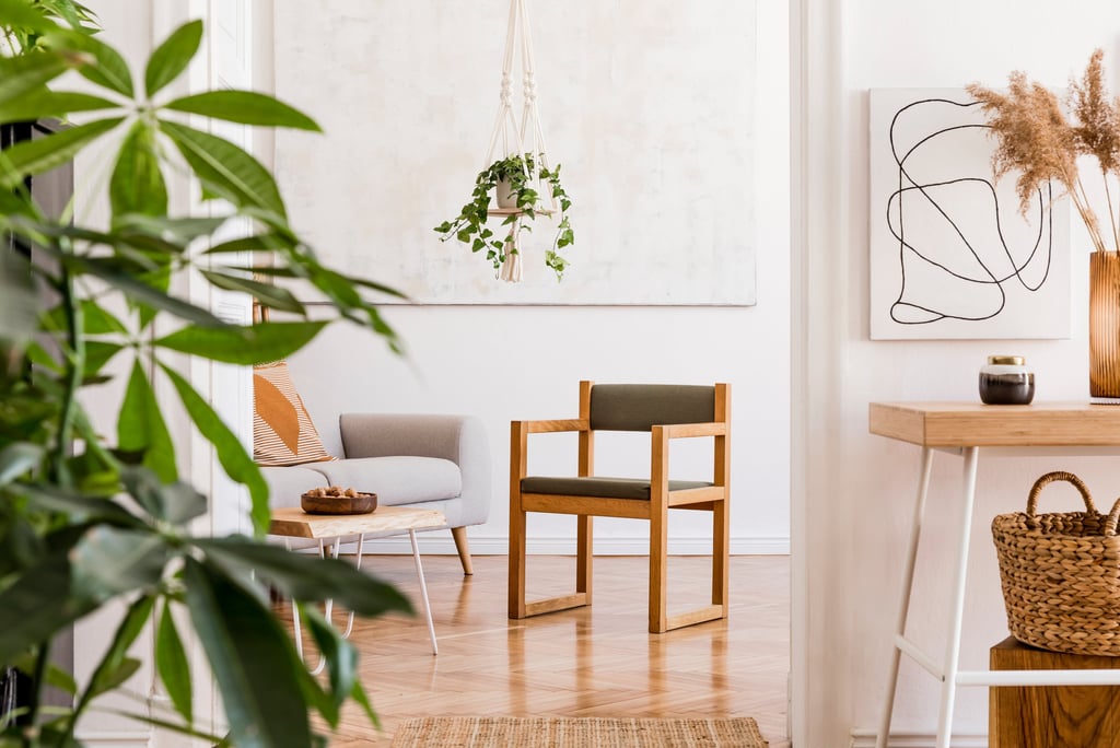 Doorkijkje in kamer met vierkante houten stoel in het midden, een sterachtige plant linksvoor.