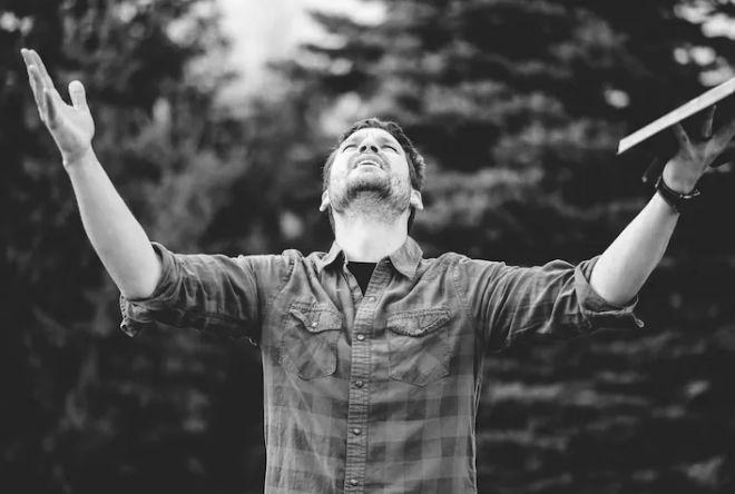 a man with his arms up and arms wide open, holding a frisbee