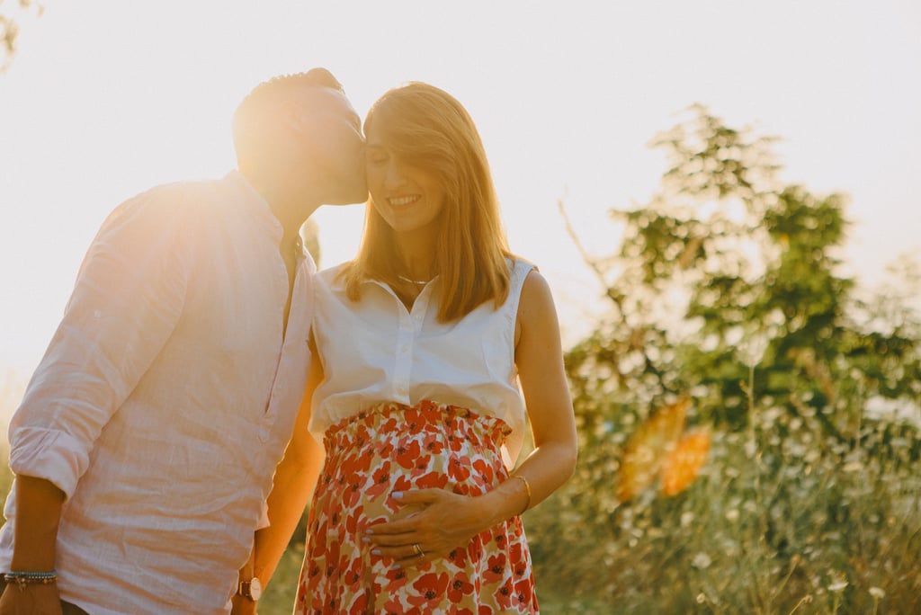 una donna incinta e un uomo che si baciano al tramonto