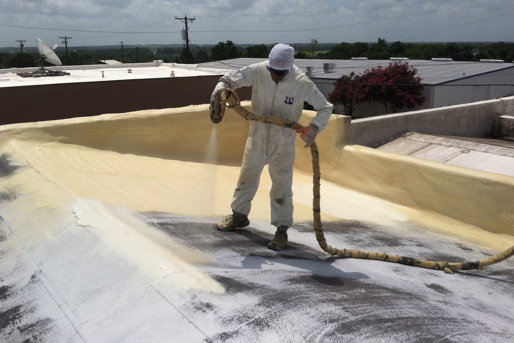 a man in a white suit and a hose on a roof