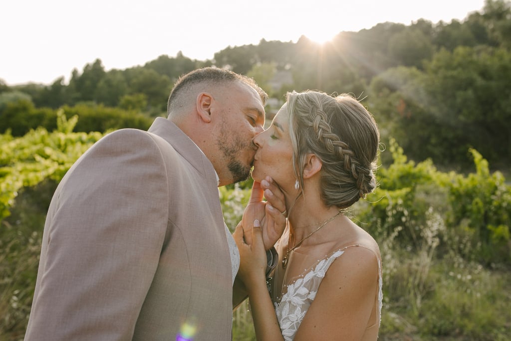 un couple jeune marié qui s'embrasse au coucher du soleil au milieu des vignes